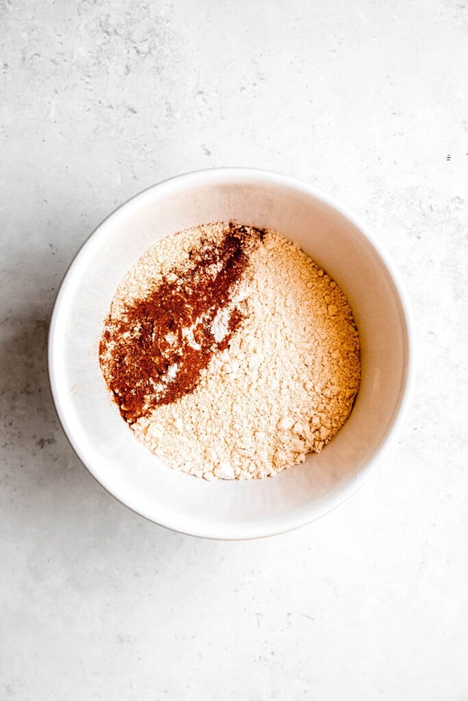 dry healthy muffin ingredients added to a mixing bowl.