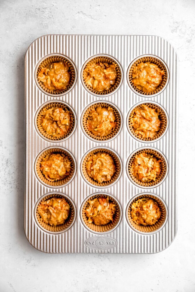 zucchini carrot muffin batter divvied up into a lined muffin tin.