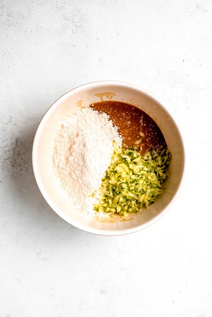 Adding the flour and shredded zucchini to the ingredients.