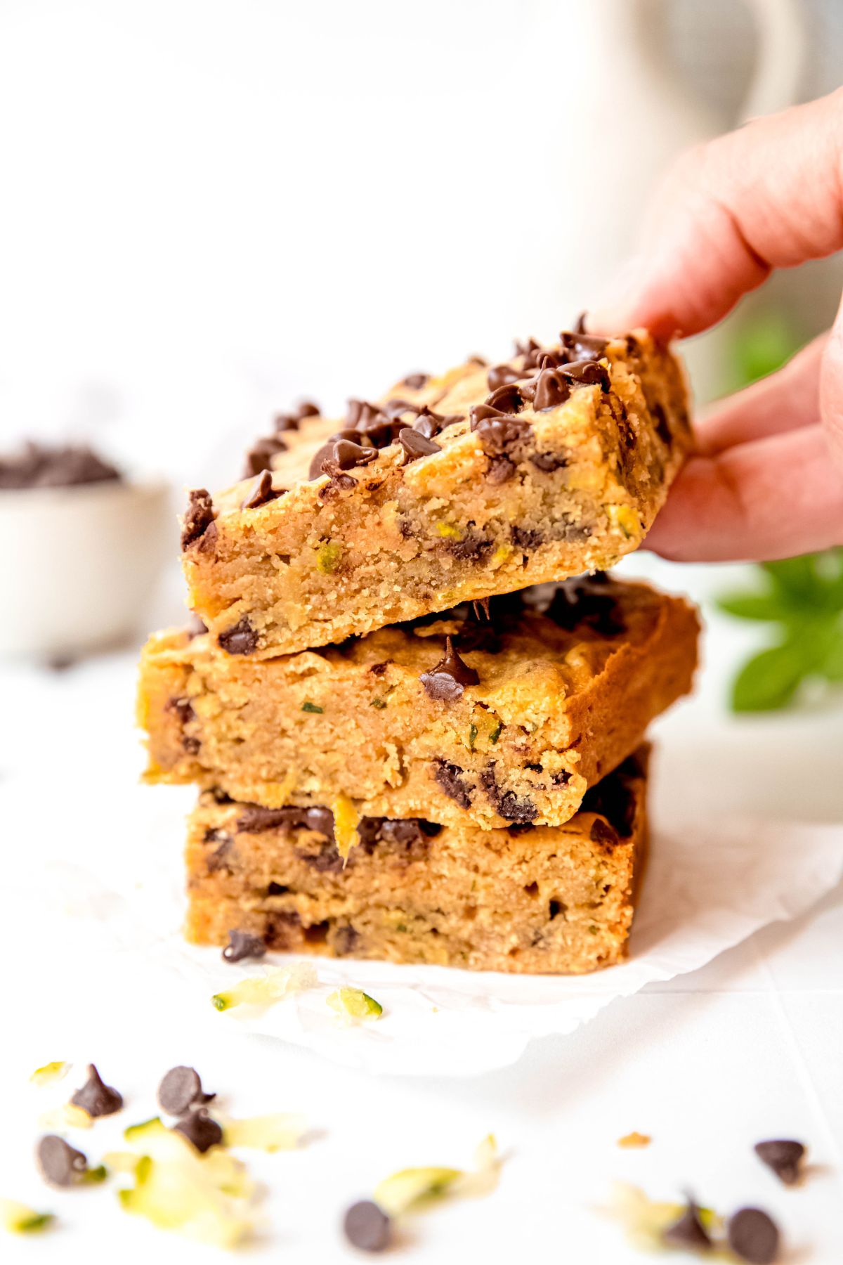 A hand grabbing a zucchini bar off a stack of 3.