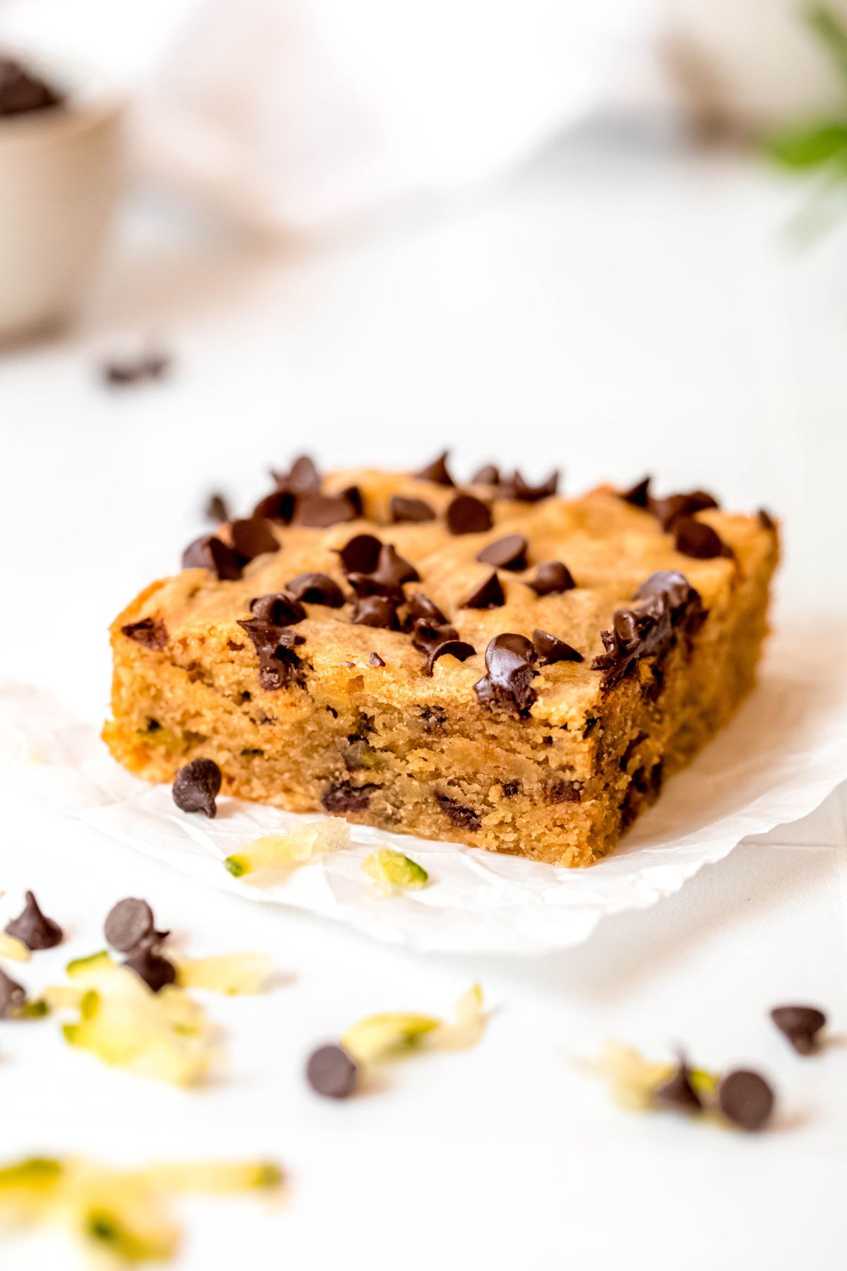 A close-up on a zucchini bar on the counter with chocolate chips and shredded zucchini.