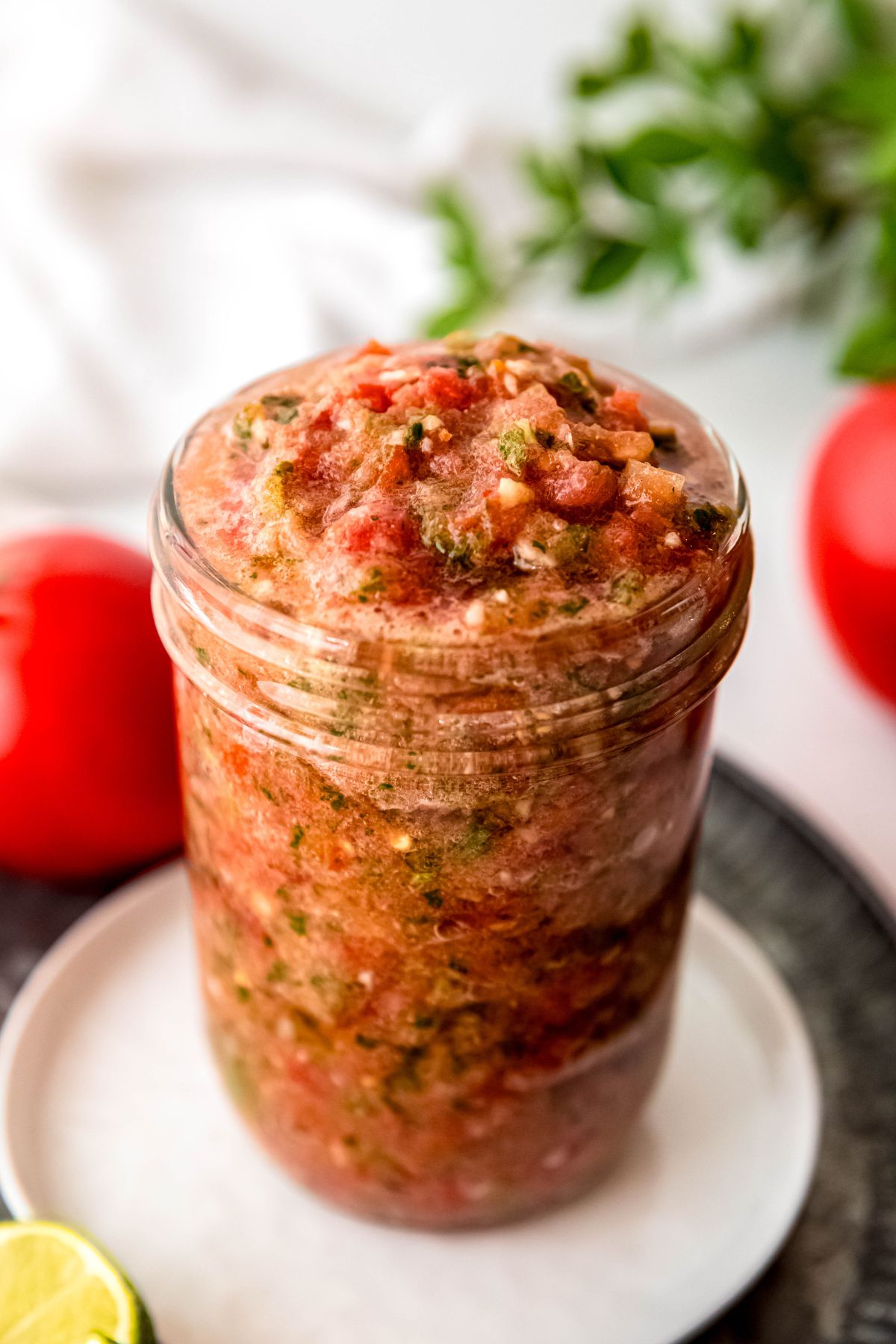 closeup 45 degree angle view of a jar of homemade fresh tomato salsa showing the slightly chunky, slightly frothy consistency.