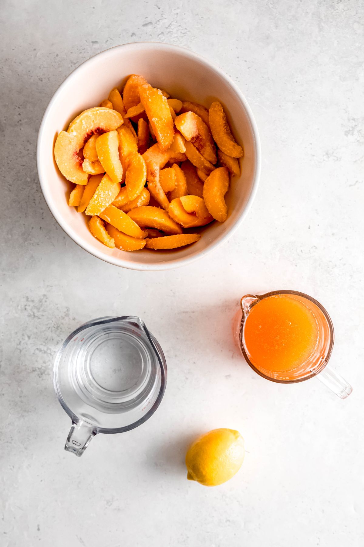 ingredients for easy peach sorbet recipe measured out on a white table.