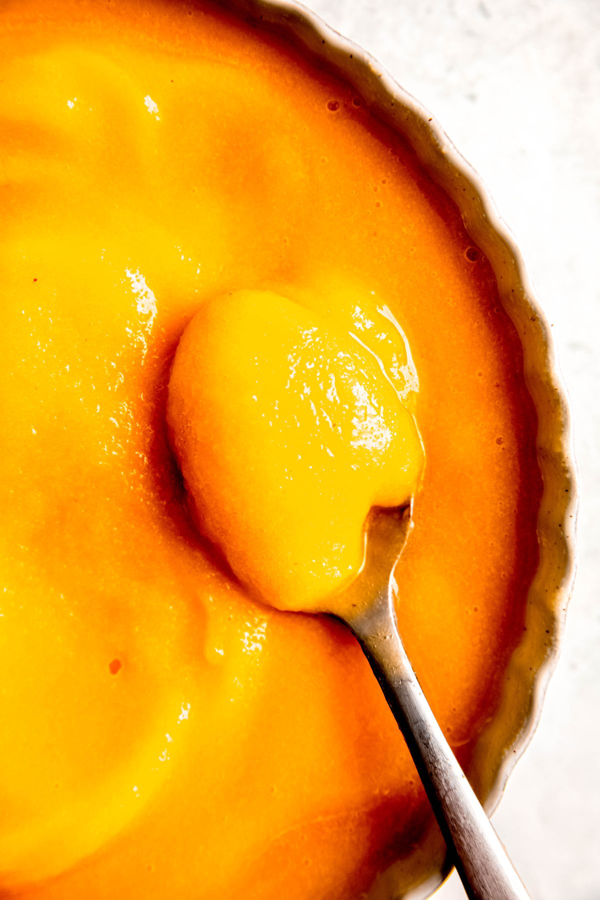 closeup shot of a silver spoonful of softened peach sorbet.