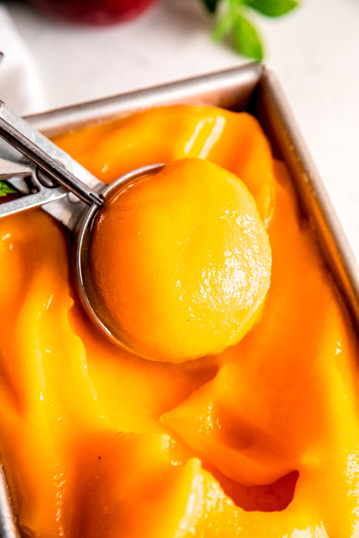 ice cream scooper taking a scoop of homemade peach sorbet.