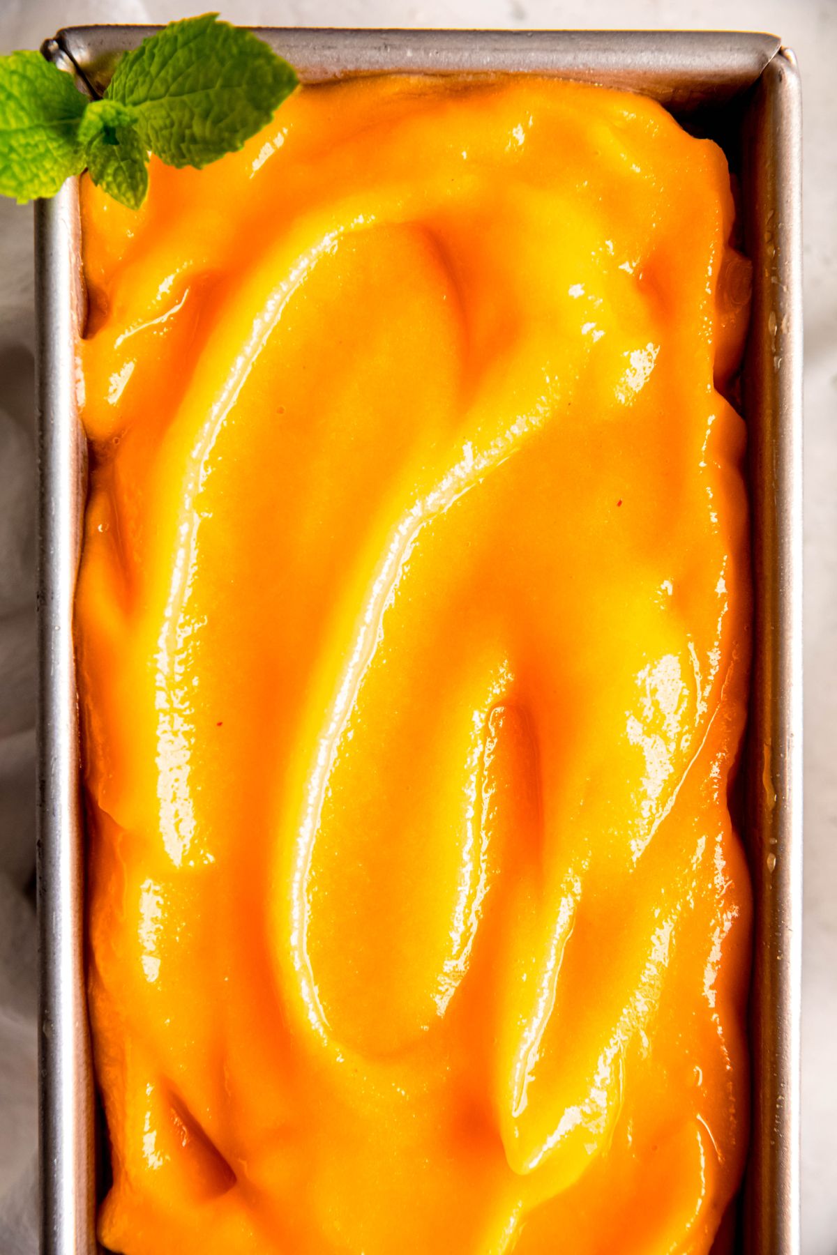 overhead shot of a metal loaf tin filled with homemade peach sorbet.