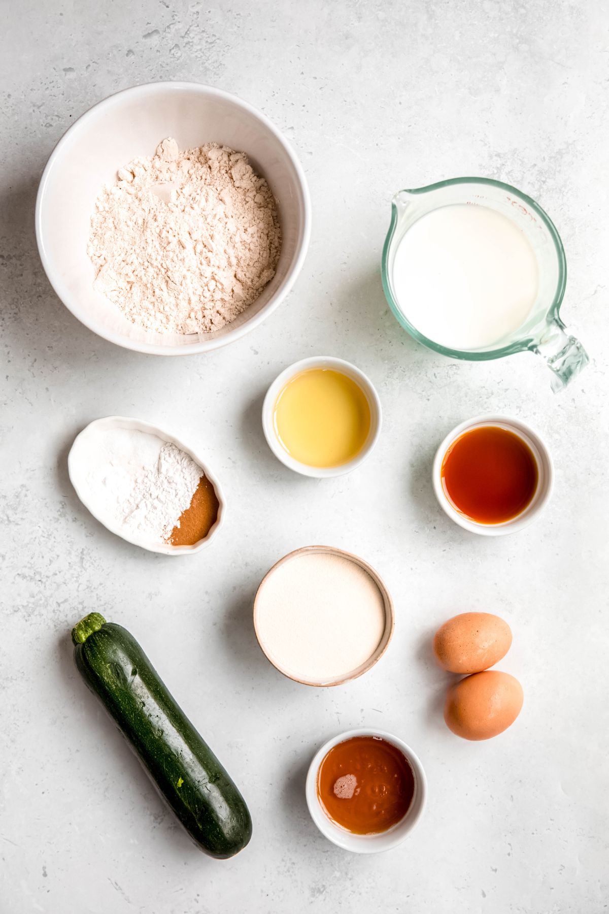 ingredients for making high protein zucchini pancakes recipe measured out on a white table.