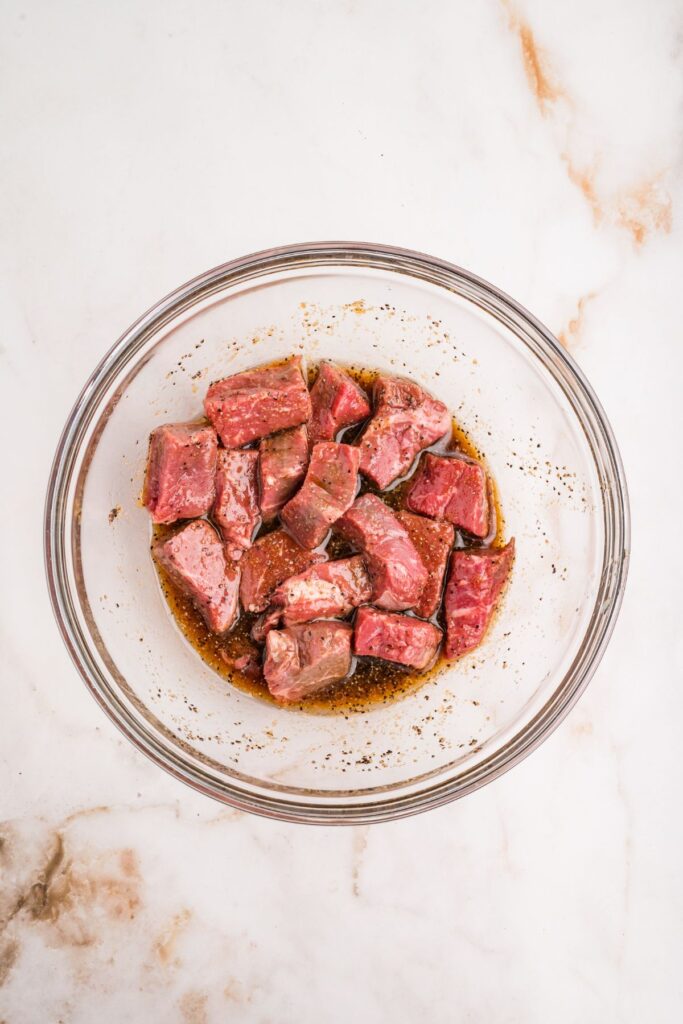 cubed sirloin added to the bowl with the marinade.