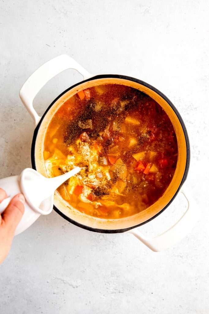 Adding the milk to the pot of simmered soup.