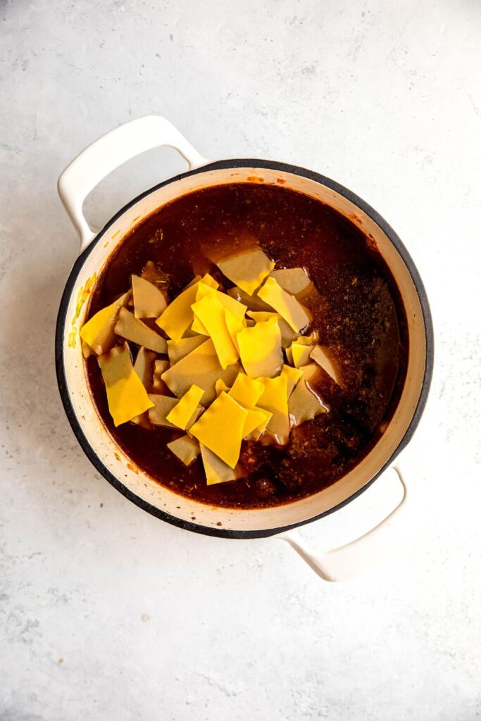 A white dutch oven of the lasagna soup with the lasagna sheet chunks added.