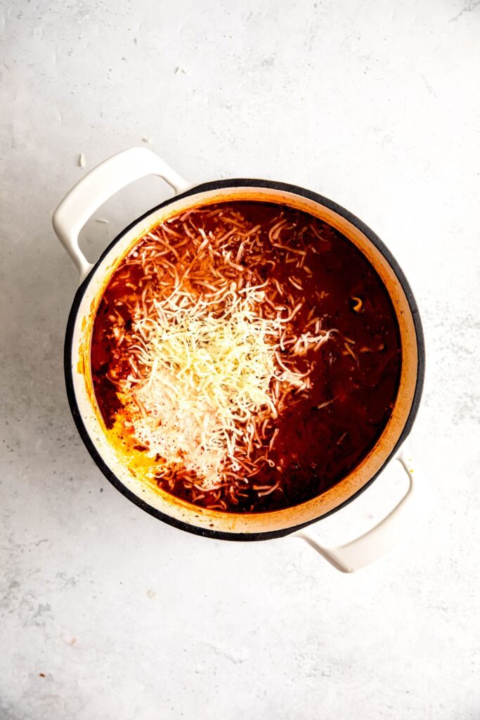 The pot of lasagna soup with shredded cheese added.