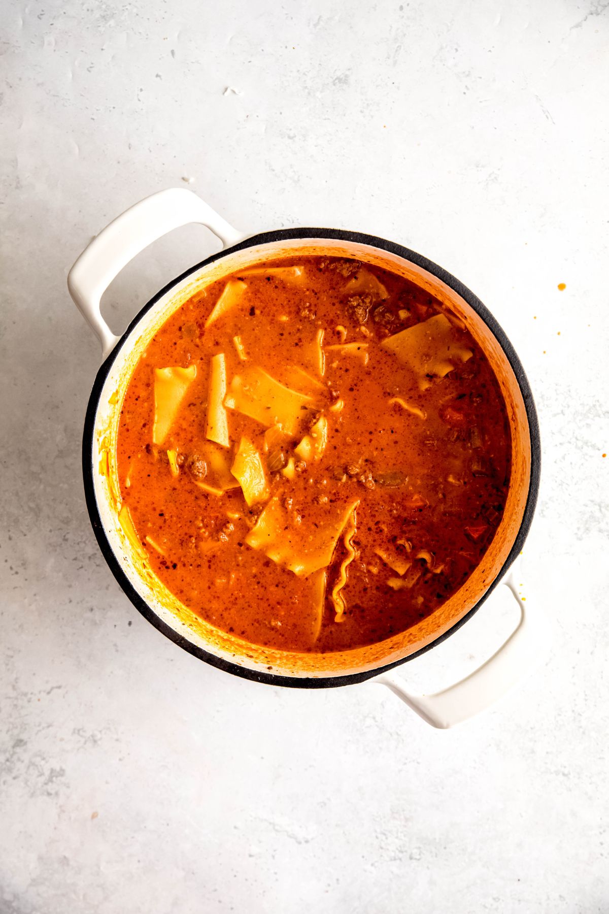 An overhead shot of a white pot of lasagna soup on the counter.