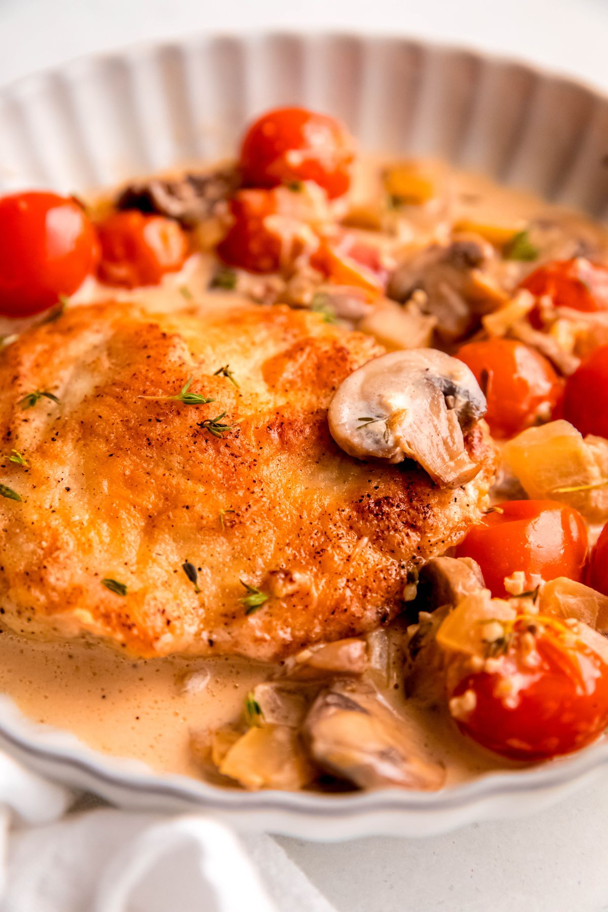 A close-up shot of a serving of the creamy mushroom chicken and tomatoes.