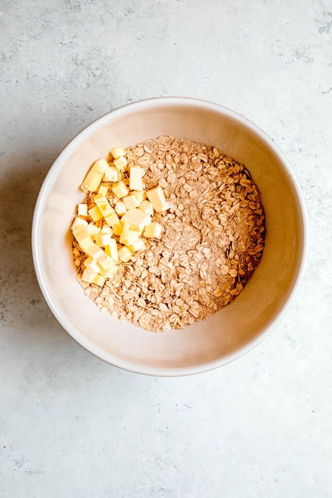 cubed butter added to a mixing bowl with the dry crisp topping ingredients.