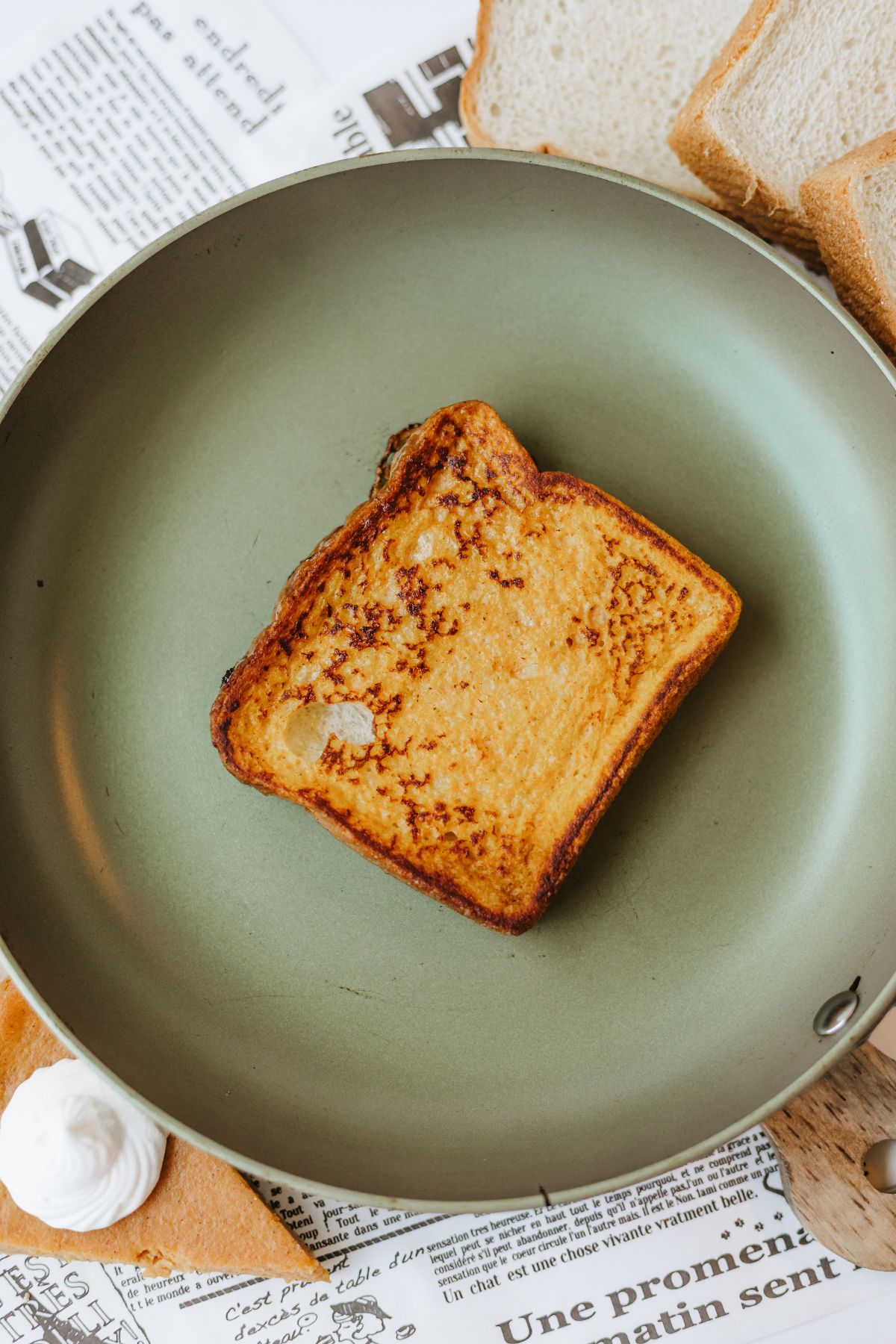 plain, undressed slice of golden brown pumpkin spiced french toast in a nonstick skillet.