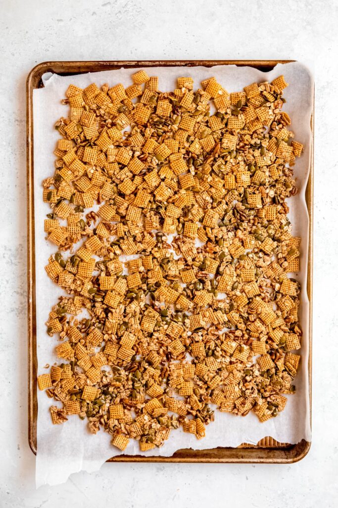 fall chex mix spread out on a parchment-lined baking sheet to bake before adding the fruit.