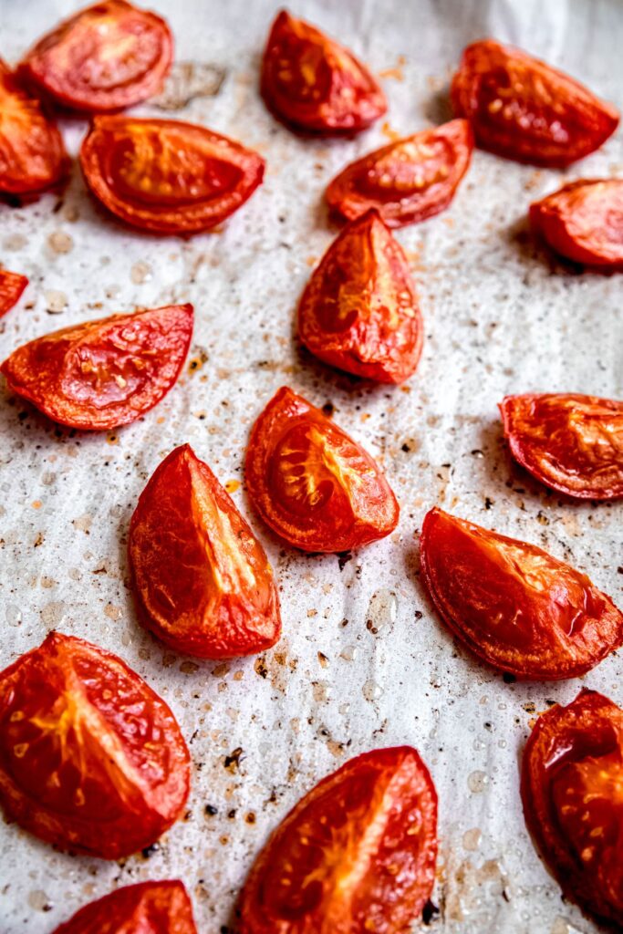 roasted quartered tomatoes on a parchment lined sheet pan.
