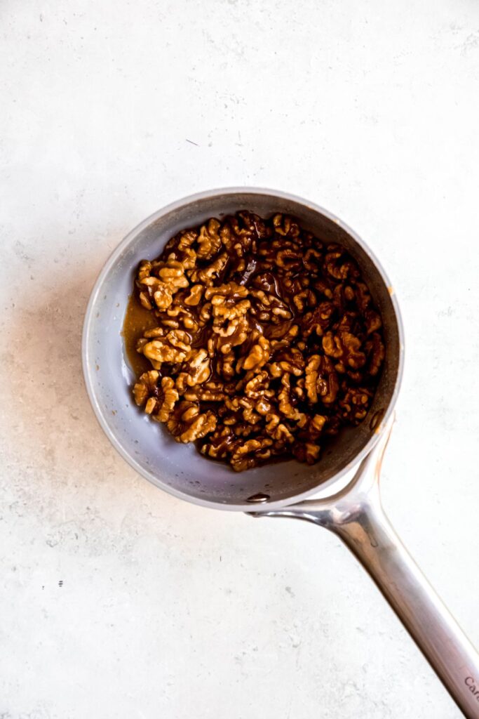 candied walnuts tossed in the brown sugar butter caramel sauce in the saucepan.