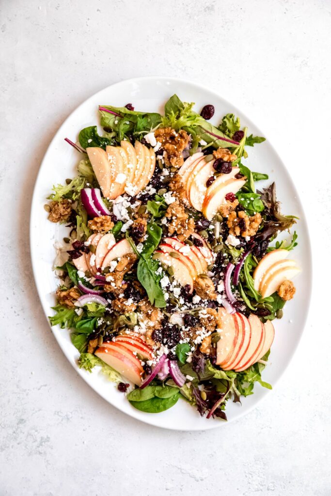 apple cranberry walnut salad after adding the dried fruit, crumbled feta, and a drizzle of apple dressing.