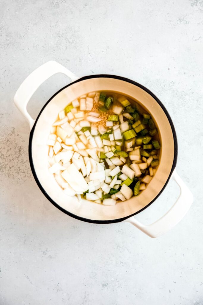 soup aromatics simmering in low sodium broth in a white dutch oven.