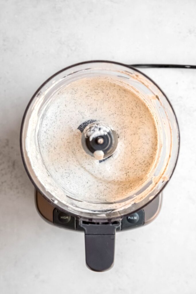 An overhead shot of the Greek yogurt ranch dressing in the bowl of the food processor.
