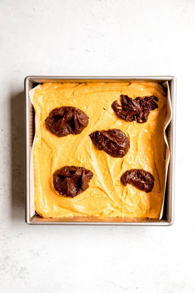 A few dollops of brownie batter on the top of the pan of the pumpkin layer before spreading.