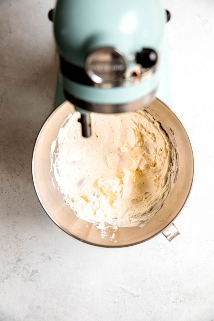 An overhead shot of a stand mixer creaming cream cheese.