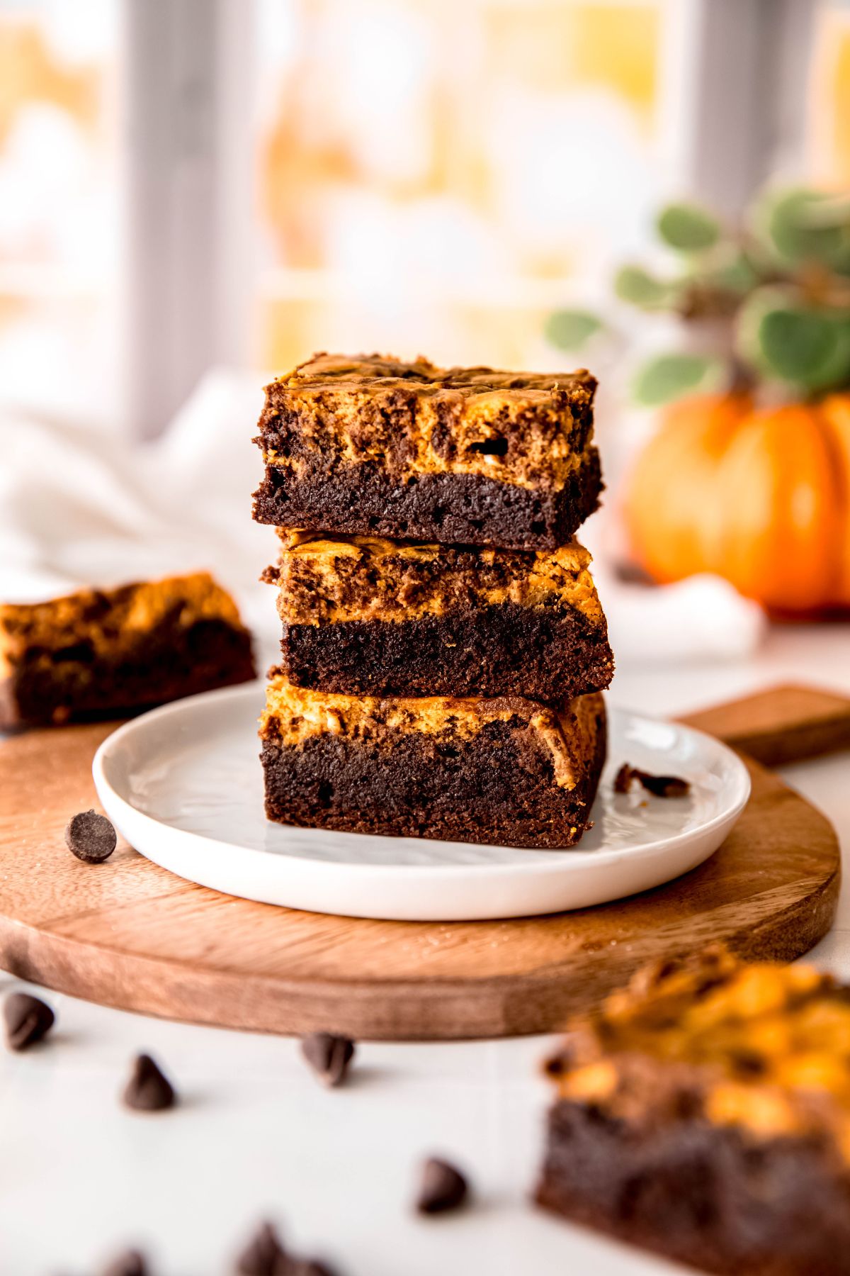 A side shot of a stack of pumpkin brownies on a white dessert plate.