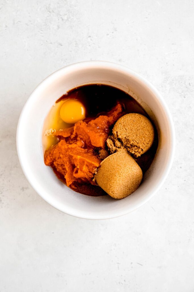 pumpkin pie filling ingredients added to a mixing bowl.