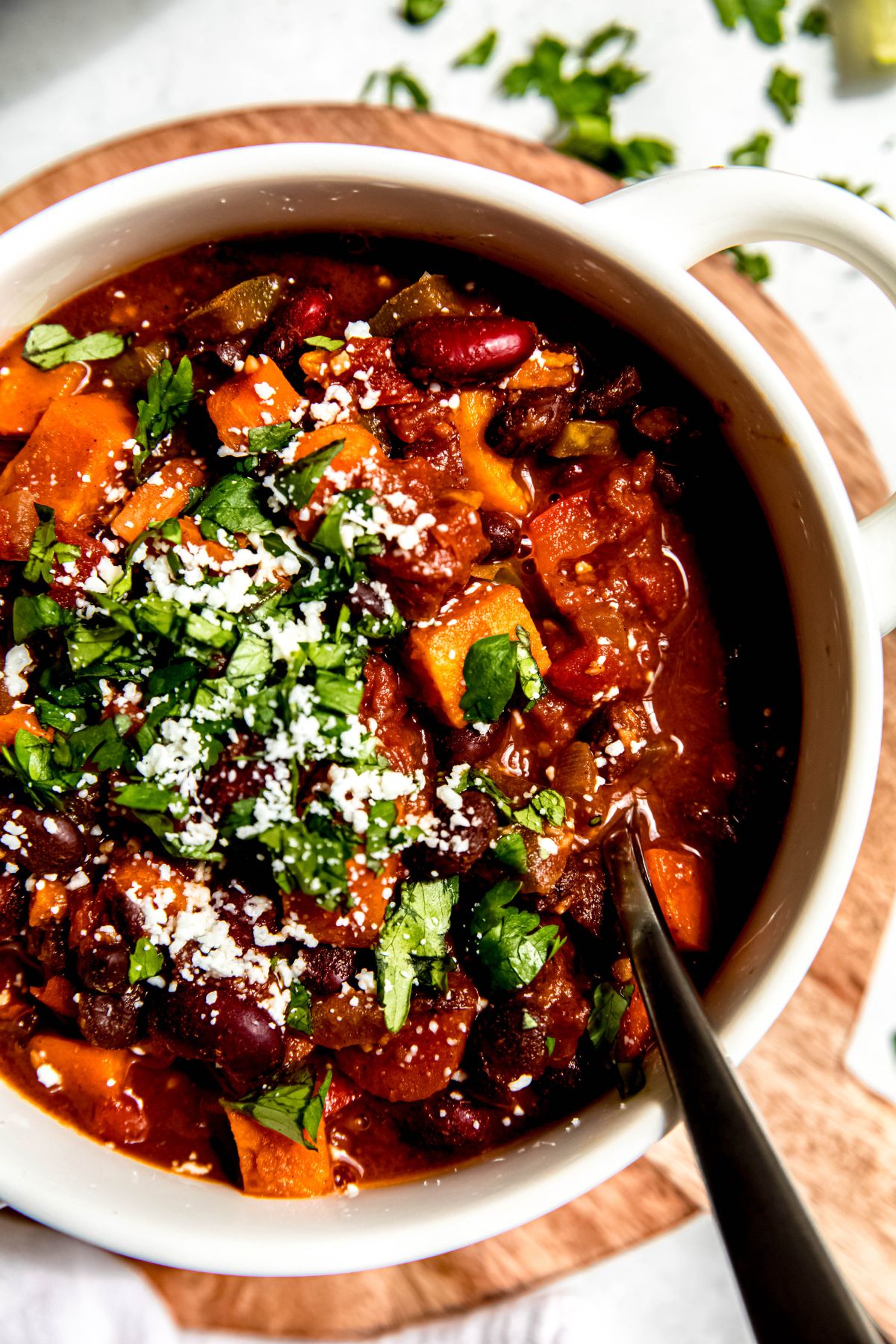 A close-up shot of a crock of sweet potato chili with a spoon in it.