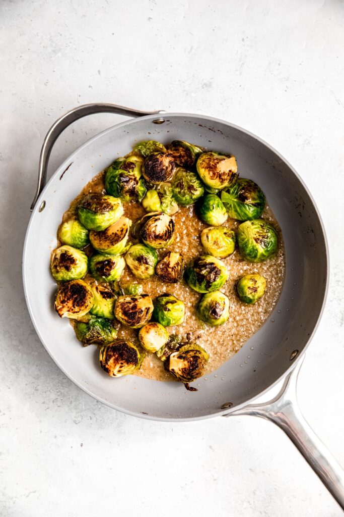 brussels sprouts tossed with the maple dijon sauce simmering in the skillet to caramelize.