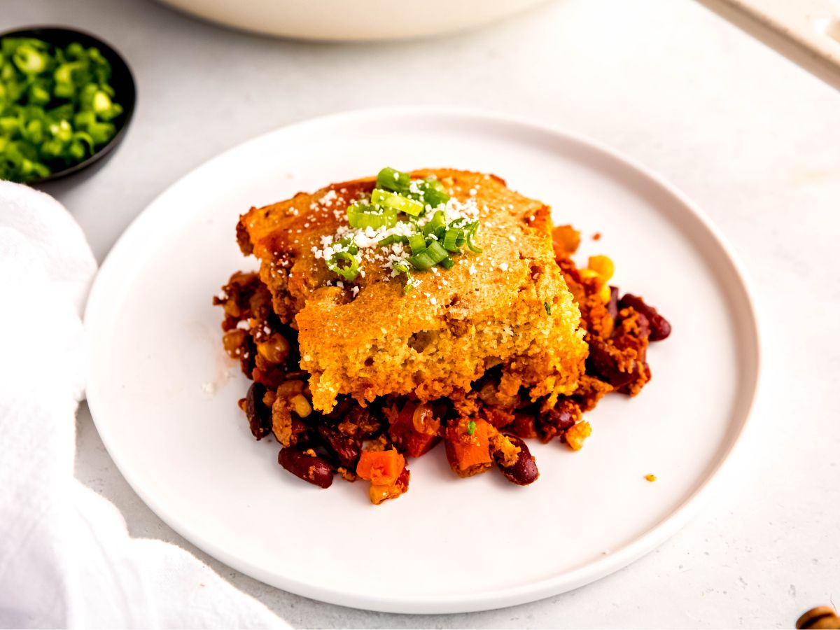 A horizontal shot of a serving of the cornbread chili casserole on a white plate.