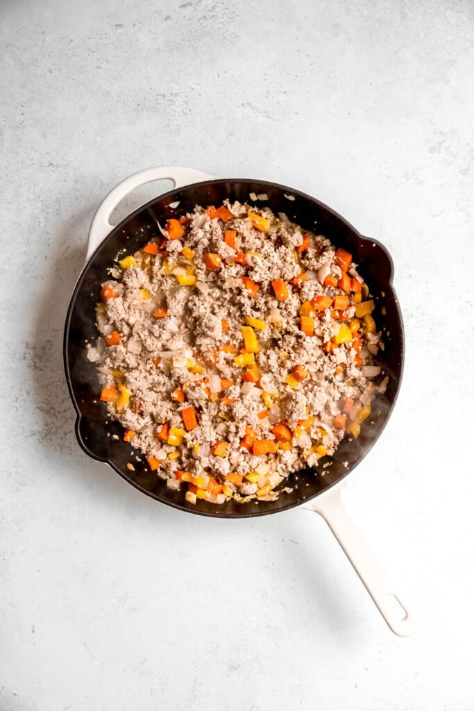 Cooked ground turkey, peppers, and onions in a skillet.