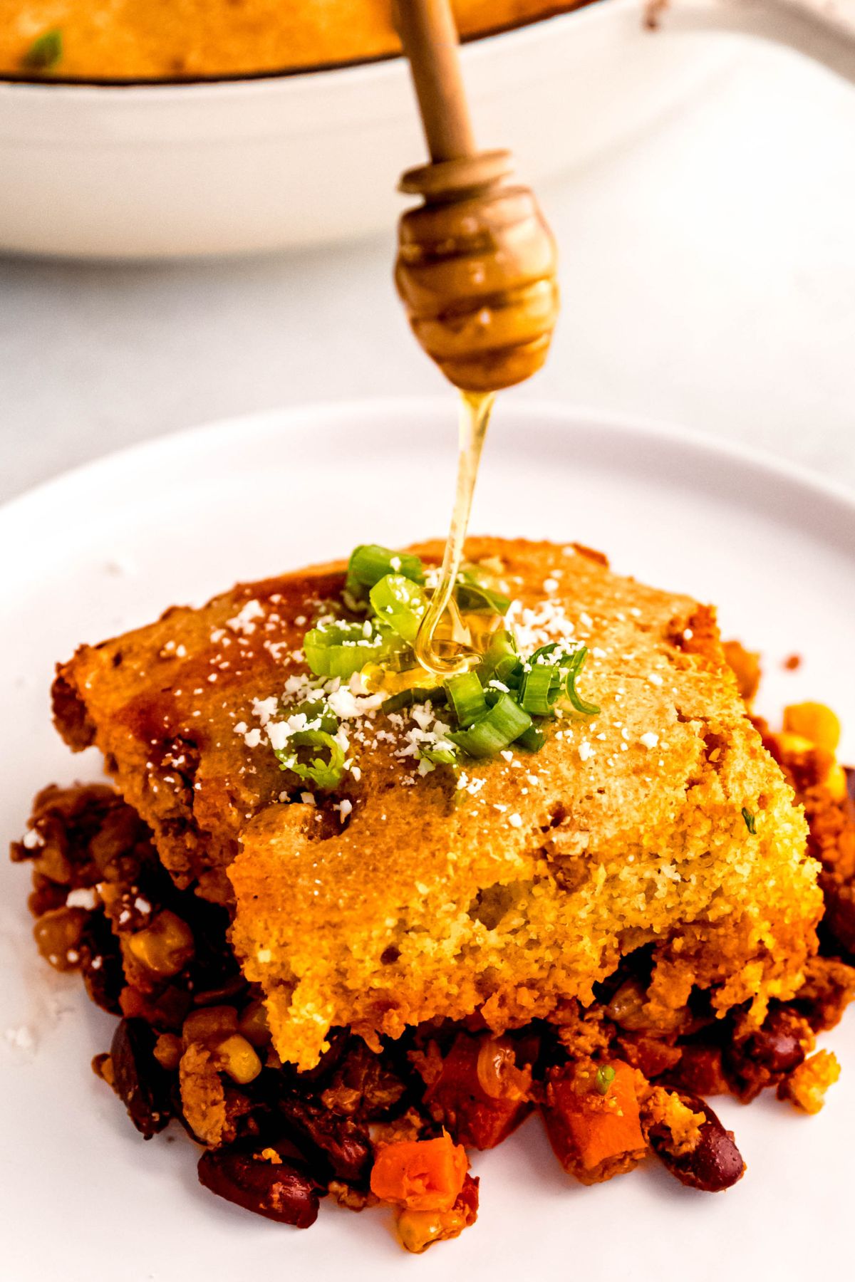 Drizzling honey on an individual serving of the chili cornbread casserole.