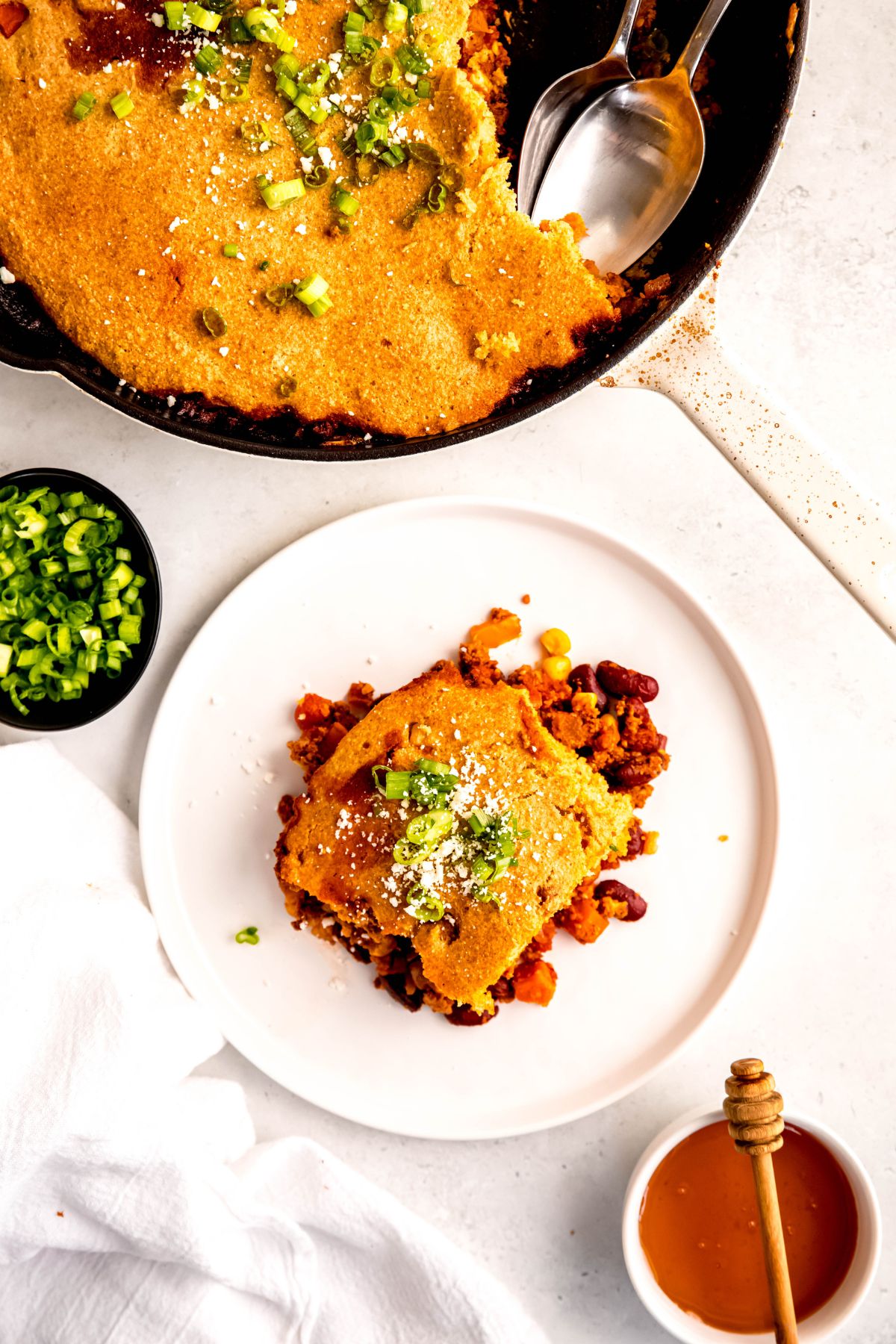 An overhead shot of an individual serving of the chili cornbread casserole on a plate next to the baking pan.