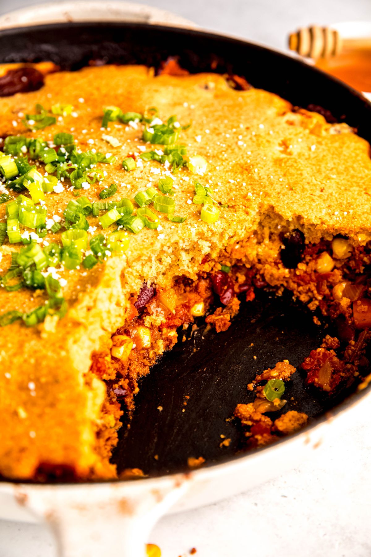 A close-up shot of a pan of the cornbread chili casserole with a serving scooped out.