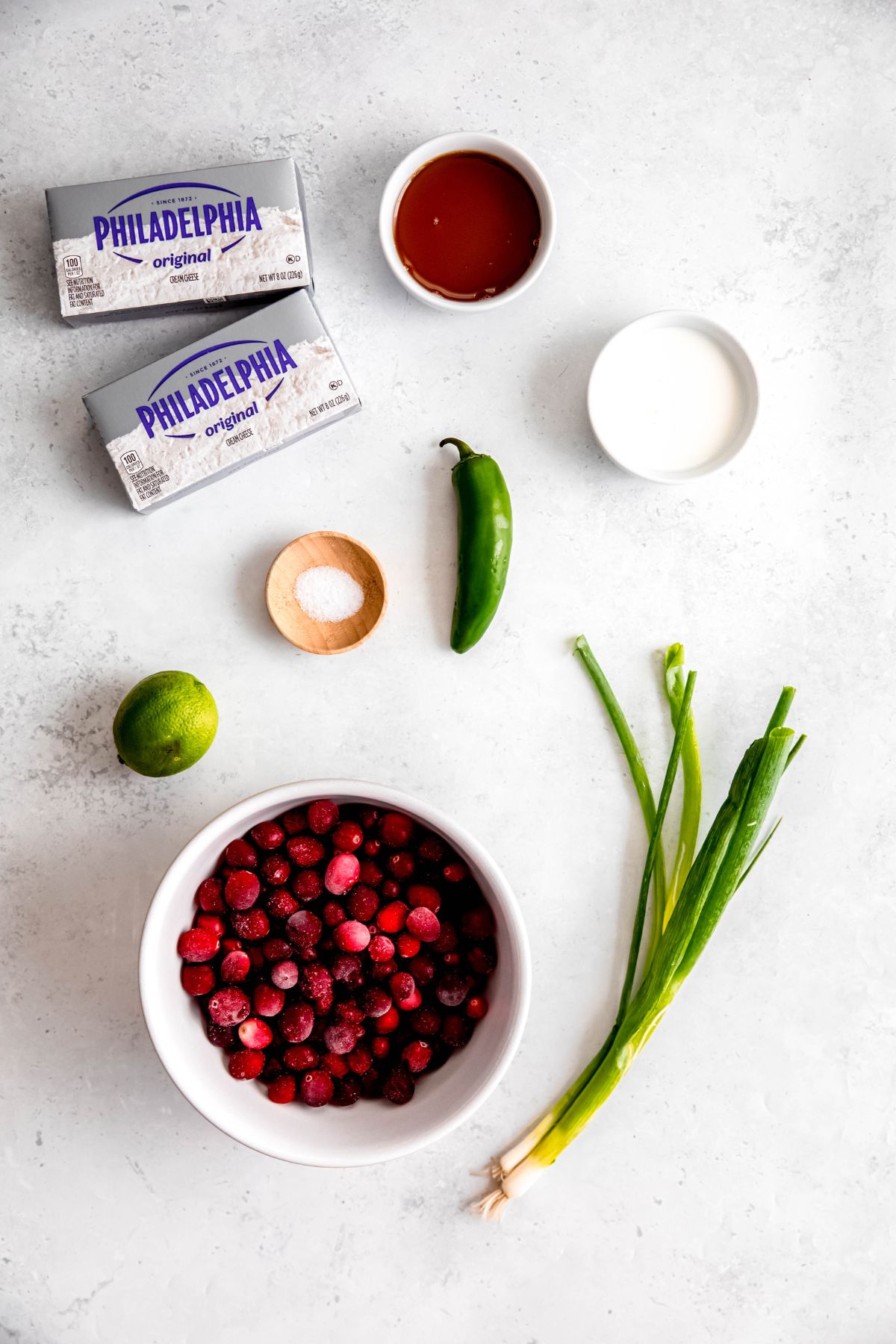 ingredients needed for making cranberry jalapeno dip with cream cheese measured out on a white table.