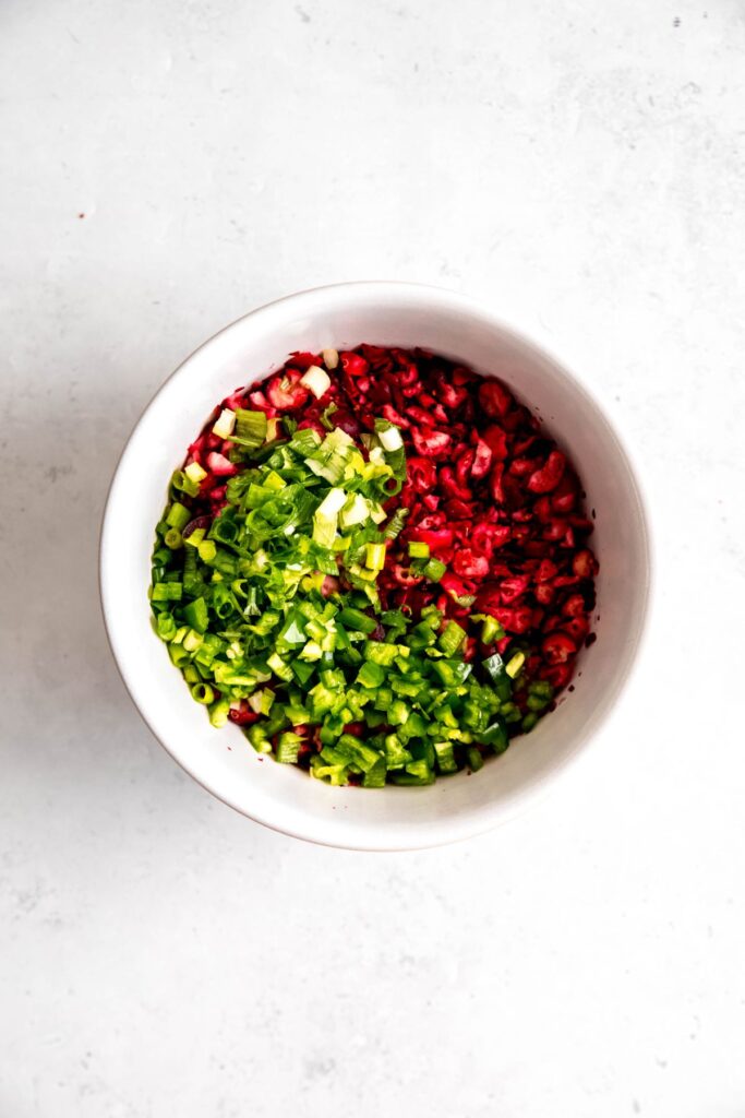 jalapenos added to a mixing bowl with the chopped cranberries.