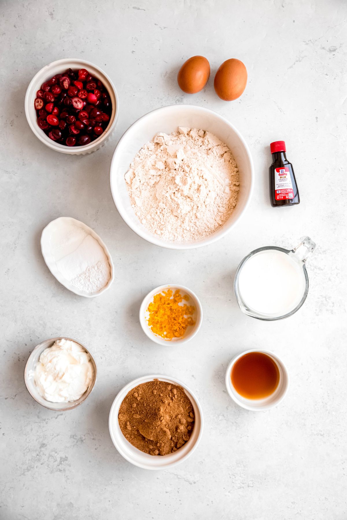 ingredients needed to make healthy cranberry orange bread measured out on a white table.