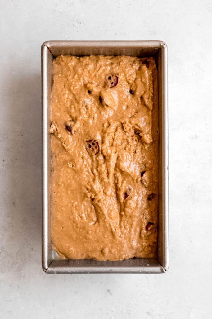 uniform orange cranberry muffin batter poured into a loaf pan.