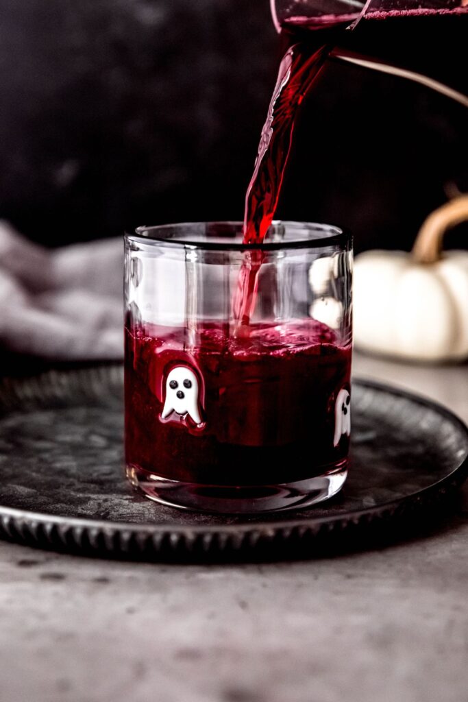 Pouring the halloween lemonade into a small glass with ghosts on it.