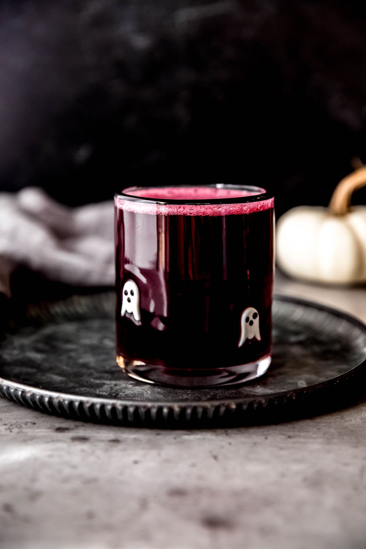 A side shot of a glass of Halloween lemonade on a metal tray.