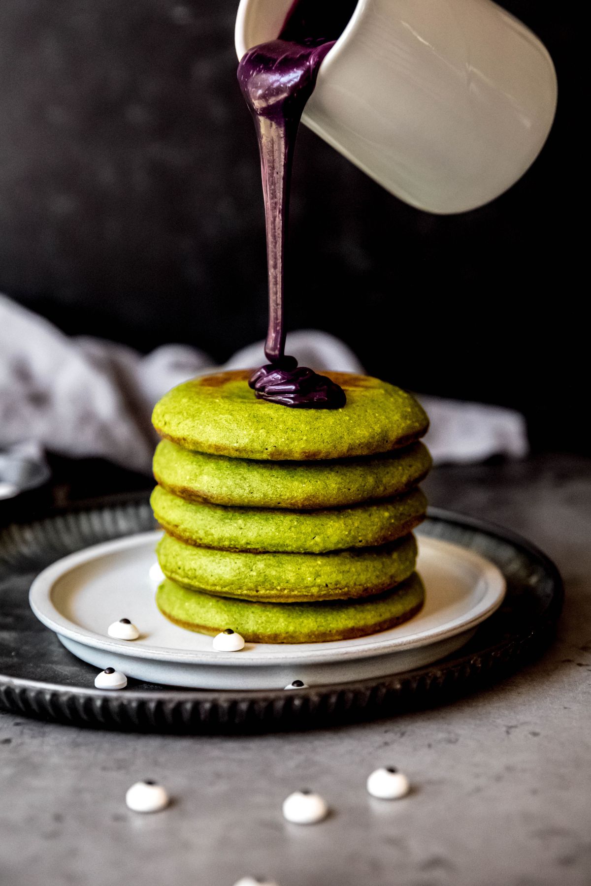 Pouring the ube syrup on the stack of green spinach pancakes.