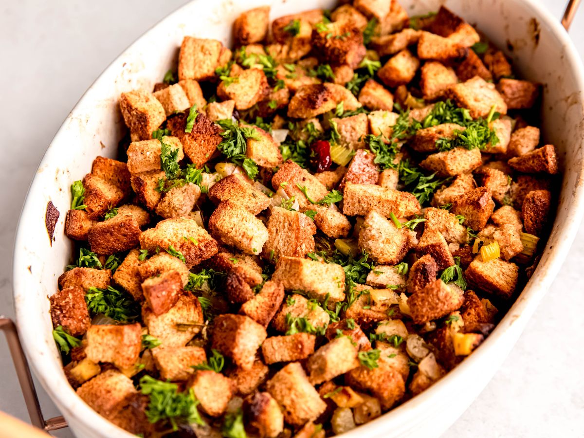 horizontal hero shot of a white casserole dish filled with baked make ahead stuffing on a white table.