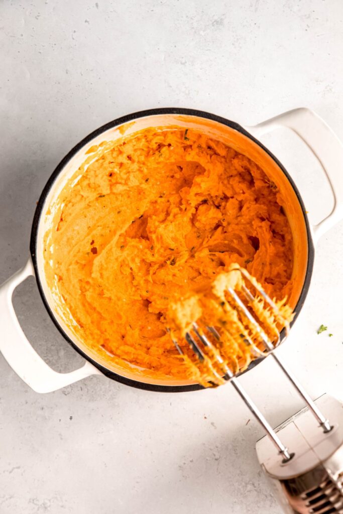 hand mixer used to mash the sweet potatoes with herbs, garlic, milk, butter, and greek yogurt until creamy.