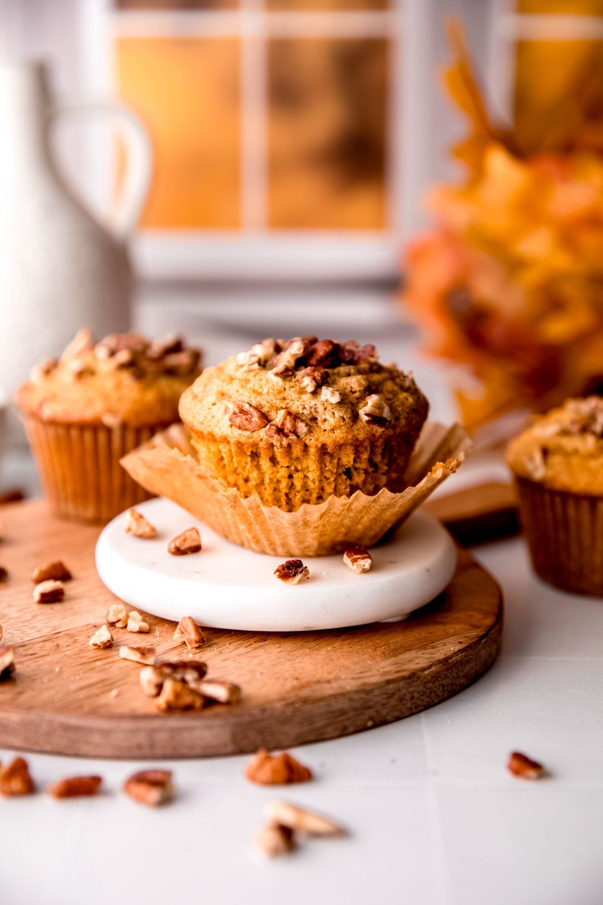 pecan pie muffin with the wrapper pulled away from the sides with two more muffins on either side blurred out.