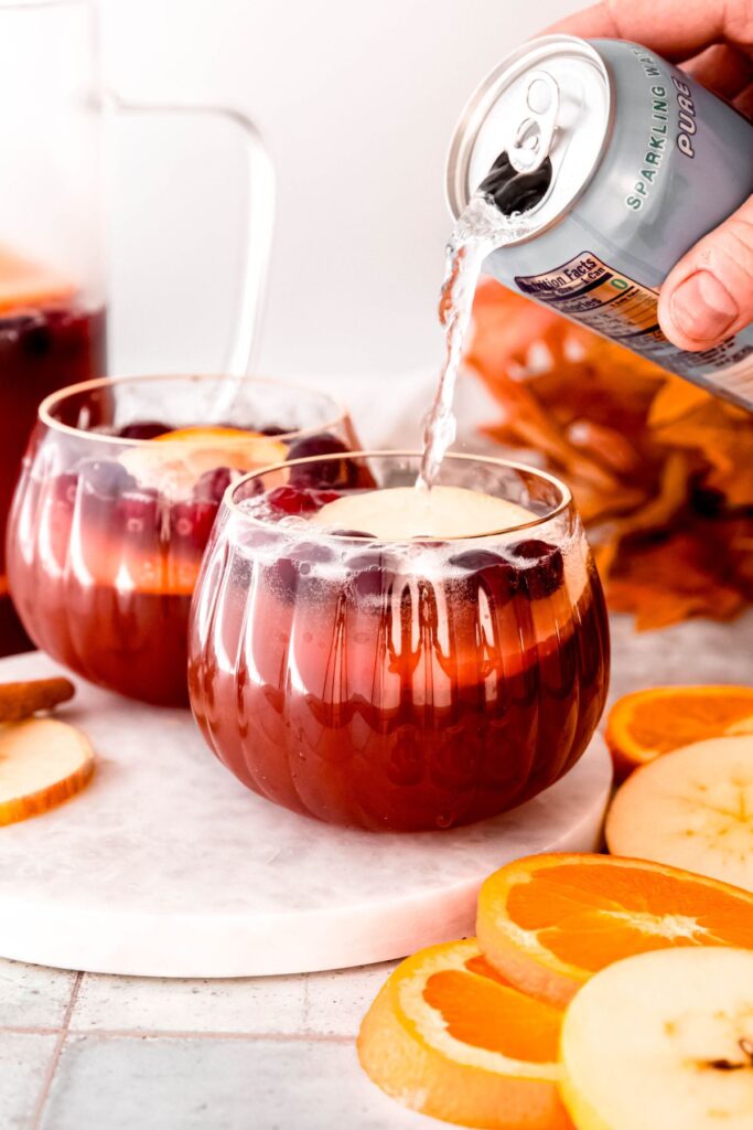 action shot of sparkling water being poured atop the punch for sparkle.