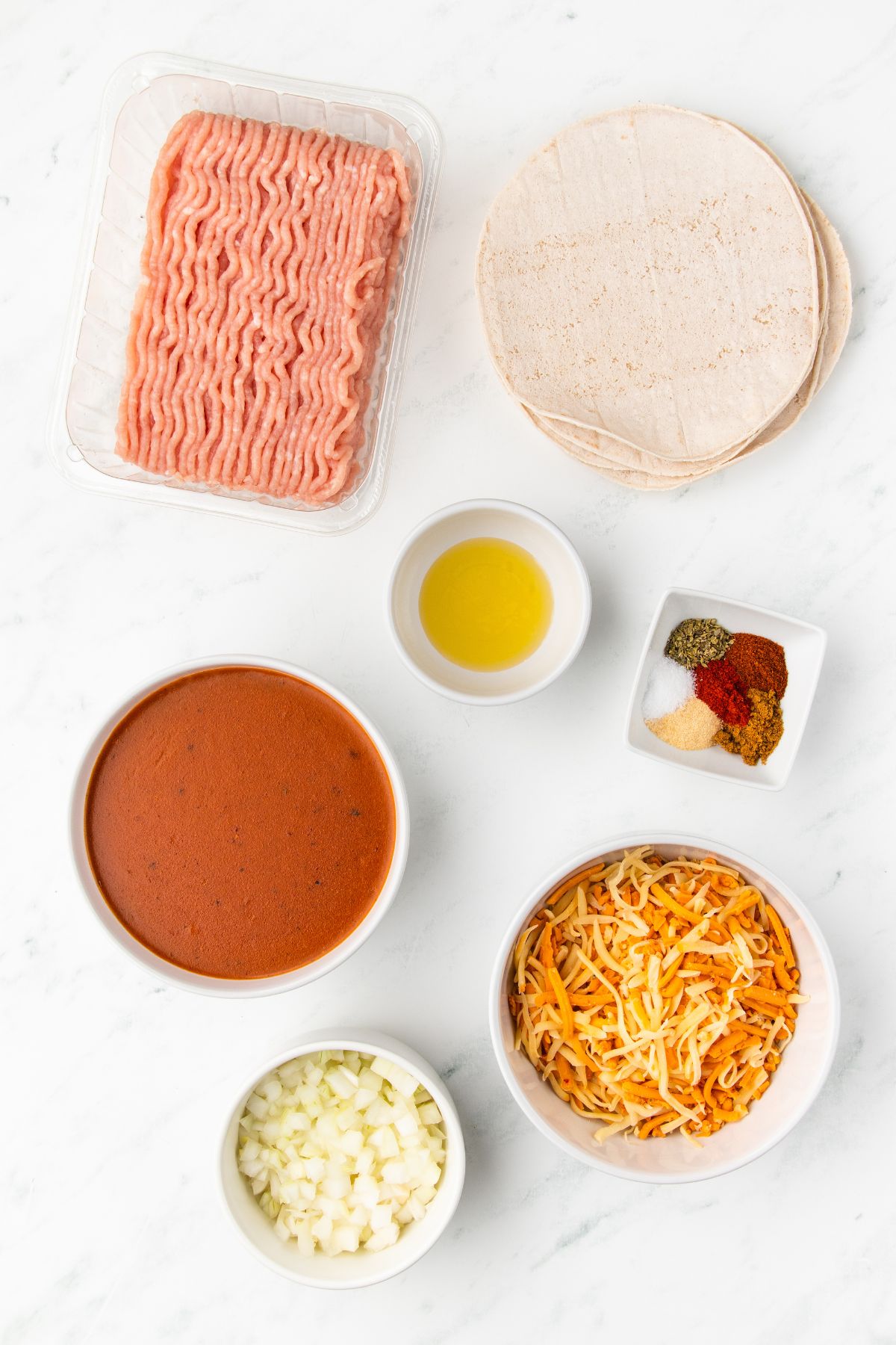 ingredients for making ground turkey enchiladas recipe measured out on a white table.