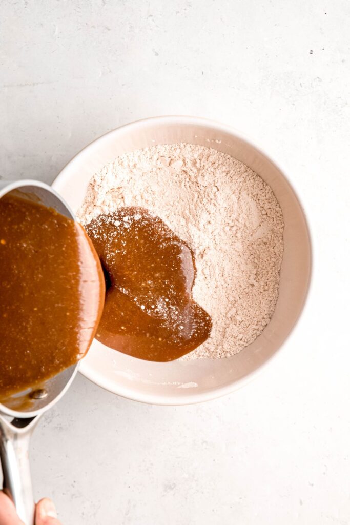 action shot of the butter-egg mixture being poured into a mixing bowl with the dry ingredients.