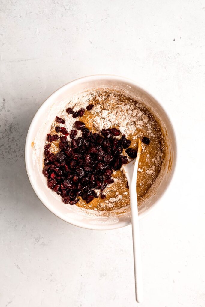dried cranberries added to the mixing bowl with the mostly mixed blondie batter; there are still some streaks of flour mixture.